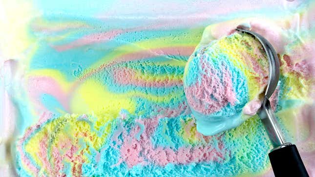 Rainbow ice cream being scooped from tub