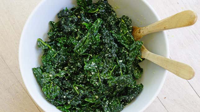 Fresh kale salad in bowl with tongs