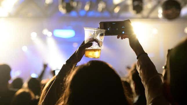 Concert attendee with beer and phone in hand